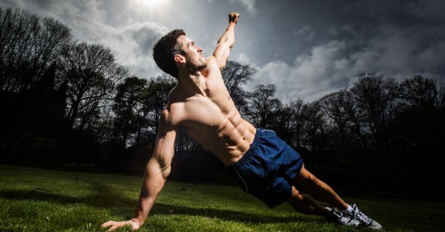 Muscular Guy in Blue Shorts Doing Planks Outdoors