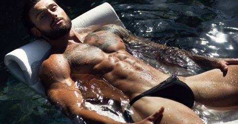 Hunk in a Black Bikini Floating in a Pool
